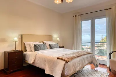 a bedroom with a large bed and a large window at Lidia's Place, a Home in Madeira in Ponta do Sol