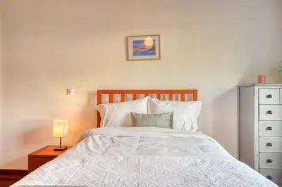 a bedroom with a white bed with a lamp and a dresser at Lidia's Place, a Home in Madeira in Ponta do Sol