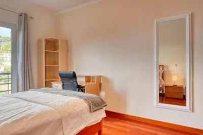 a bedroom with a bed and a chair and a mirror at Lidia's Place, a Home in Madeira in Ponta do Sol
