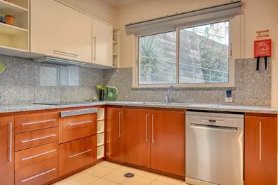 a kitchen with wooden cabinets and a window at Lidia's Place, a Home in Madeira in Ponta do Sol