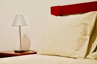 a bed with a pillow and a lamp on a table at Apartamento da vila, Porto Santo. in Vila Baleira