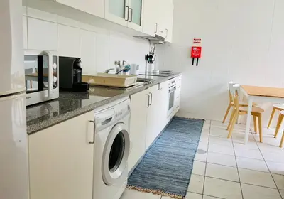 a kitchen with a washing machine and a table at Apartamento da vila, Porto Santo. in Vila Baleira