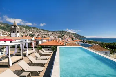 a pool on the roof of a building with lounge chairs at Barceló Funchal Oldtown in Funchal
