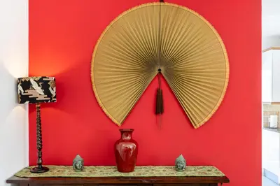 a red wall with a mirror and a vase on a table at Casa Da Bauhinia in Aljezur