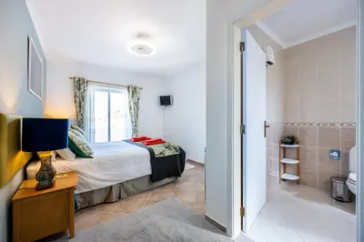a bedroom with a bed and a bathroom at Casa Da Bauhinia in Aljezur