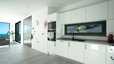 a kitchen with white cabinets and a tv on the wall at Casa Erbozeta by LovelyStay in Funchal