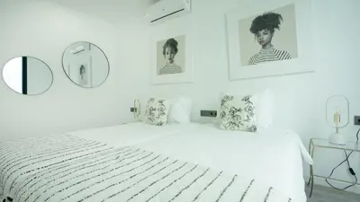 a white bedroom with a bed and a mirror at Casa Erbozeta by LovelyStay in Funchal