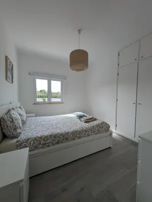 a white bedroom with a bed and a window at Casa Oliveira in Sagres
