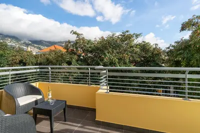 a balcony with a yellow railing and a table and chairs at Art Deco Central Apartments, Funchal in Funchal
