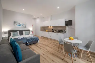 a living room with a couch and a table and a kitchen at Art Deco Central Apartments, Funchal in Funchal