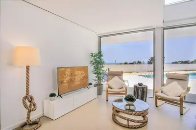a living room with a television and a table and chairs at Ocean view Architectural Modern Villa in Burgau