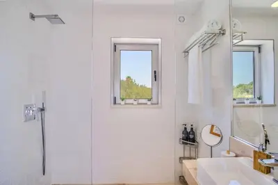 a white bathroom with a shower and a sink at Ocean view Architectural Modern Villa in Burgau