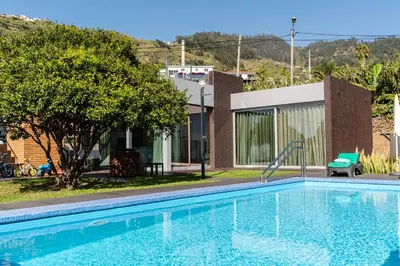 a swimming pool with a slide in front of a house at Calheta Tangerine House in Arco da Calheta