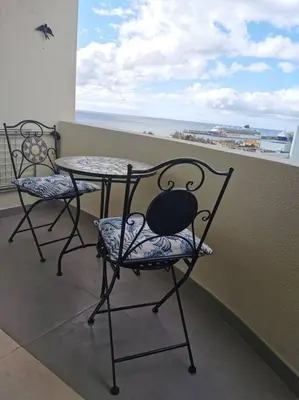 a table and chairs on a balcony with a view of the ocean at Alegria A in Funchal