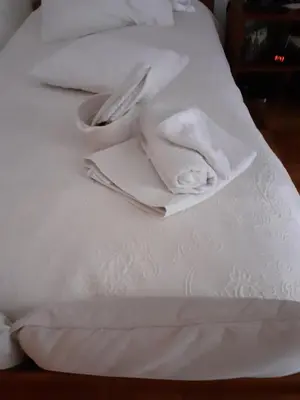 a white bed with white towels and a fork and knife at Cantinho da Maria in Funchal
