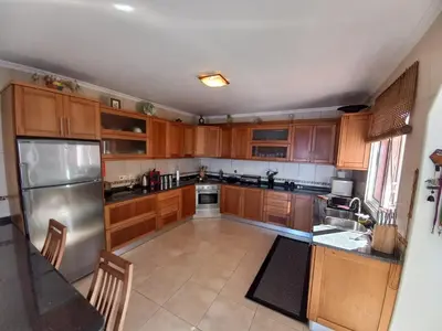 a kitchen with wooden cabinets and a stainless steel refrigerator at Casa Abreu Gouveia in Ponta do Pargo in Calheta