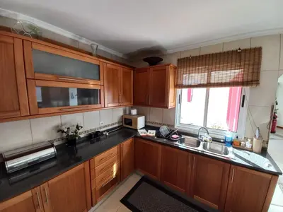 a kitchen with wooden cabinets and a sink and a window at Casa Abreu Gouveia in Ponta do Pargo in Calheta