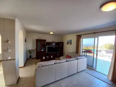 a living room with a white couch and a sliding glass door at Casa Abreu Gouveia in Ponta do Pargo in Calheta