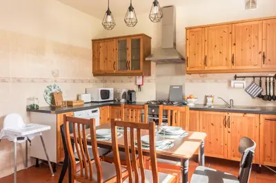 a kitchen with wooden cabinets and a table with chairs at Casa da Olides - T3 in Santana