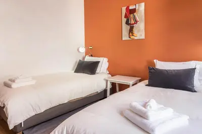 two beds in a room with orange walls at Casa da Olides - T3 in Santana