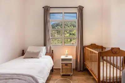 a bedroom with a crib and a window at Casa da Olides - T3 in Santana