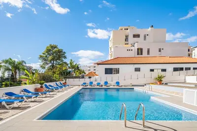 a pool with chairs and a building in the background at Casa Branca 360 - Penthouse - By Wehost in Funchal