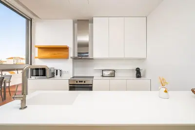 a kitchen with white cabinets and a large window at Casa Branca 360 - Penthouse - By Wehost in Funchal