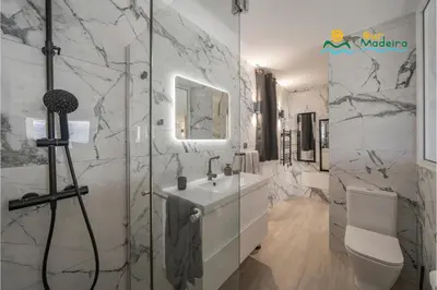 a bathroom with a sink and a toilet and a mirror at Premium quiet apt Funchal seafront Oceanbreeze in Funchal