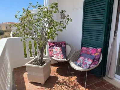 two chairs and a potted tree on a balcony at Casa Limonte in Luz