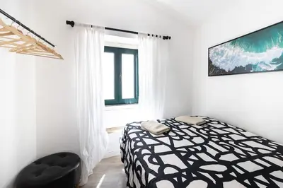 a bedroom with a black and white bed and a window at Casa Levante in Sagres