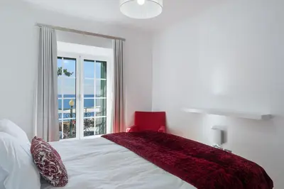 a bedroom with a bed with a red blanket and a window at Casa Clarisse by Holiday Rental Madeira in Funchal