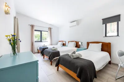 a bedroom with two beds and a table and chairs at CoolHouses Algarve, Luz, 3 Bed villa, 1 bed studio, heated pool & jacuzzi, sea views, Casa Pequena in Luz