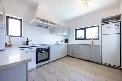 a white kitchen with white appliances and wooden floors at CoolHouses Algarve, Luz, 3 Bed villa, 1 bed studio, heated pool & jacuzzi, sea views, Casa Pequena in Luz