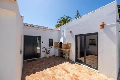 a white house with a patio with a fireplace at CoolHouses Algarve, Luz, 3 Bed villa, 1 bed studio, heated pool & jacuzzi, sea views, Casa Pequena in Luz