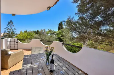 a table with wine glasses and flowers on a patio at CoolHouses Algarve, Luz, 3 Bed villa, 1 bed studio, heated pool & jacuzzi, sea views, Casa Pequena in Luz