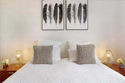 a bedroom with a white bed with three pictures on the wall at Kiara's Cantinho do Mar by Rentallido in Funchal