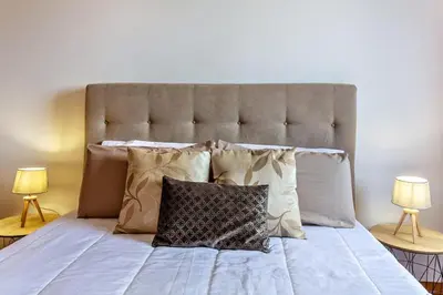 a large bed with pillows on it with two lamps at MCR Funchal in Funchal