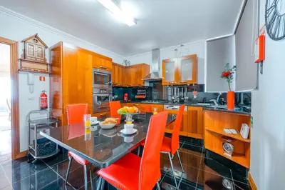 a kitchen with a dining table and orange chairs at Palm Tree House by Amazing Madeira in Câmara de Lobos