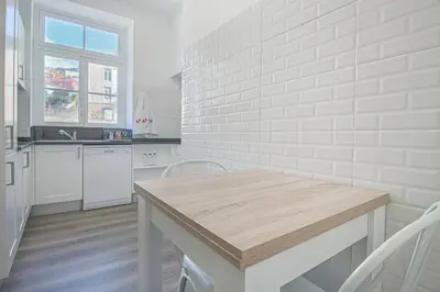 a white kitchen with a wooden table and chairs at Pi Houses in Funchal