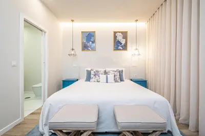 a bedroom with a large white bed with two benches at Machim D Arfet House by Homie in Machico