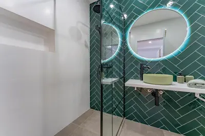 a bathroom with a green tiled wall with a mirror at FLH Funchal Spacious Apartment with Balcony in Funchal