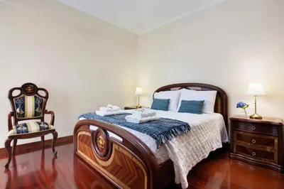 a bedroom with a large bed and a chair at Central Living Funchal in Funchal