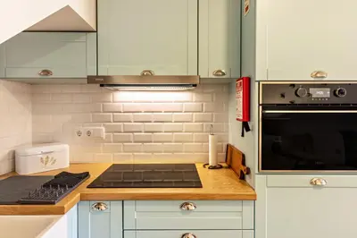 a kitchen with white cabinets and a stove top oven at Casa das Andorinhas in Câmara de Lobos