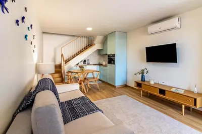 a living room with a couch and a flat screen tv at Casa das Andorinhas in Câmara de Lobos