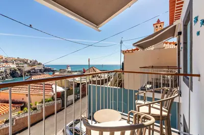 a balcony with two chairs and a view of the ocean at Casa das Andorinhas in Câmara de Lobos