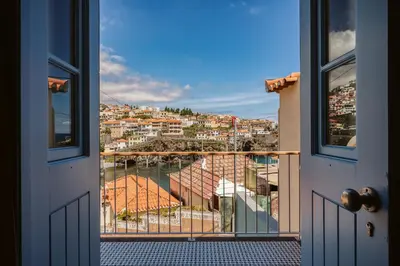 a room with a view of a city from a balcony at Casa das Andorinhas - 1 bedroom apartment sleeps 4 in Câmara de Lobos