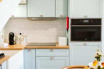 a kitchen with white cabinets and a black microwave at Casa do Calhau - 1 bedroom apartment sleeps 4 in Câmara de Lobos