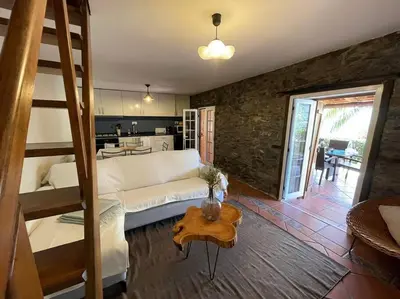 a room with a bed and a living room with a kitchen at Secluded cottage w pool, oceanside view, 3BR, 3BA in Ponta do Sol