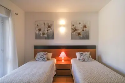 a bedroom with two beds and a table with a lamp at Casa Caravela, Praia da Luz in Luz