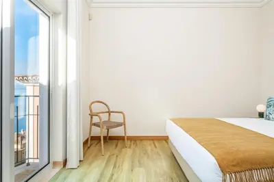 a bedroom with a bed and a chair and a window at Villa Sea Renity - Palheiro Village by ALMA Holiday Rentals in Funchal